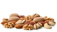 Mixed nuts collection with almonds, walnuts, pistachios and cashews isolated on white background for healthy snacking and cooking ingredients.