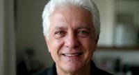 Smiling senior Caucasian businessman with gray hair in professional attire looking confident and approachable in modern office environment for corporate content.
