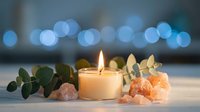 Burning candle with eucalyptus leaves and rose quartz crystals creating peaceful spa atmosphere with soft bokeh lights background for relaxation.