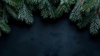 Fresh green fir branches frame dark background creating festive winter holiday atmosphere with copy space for seasonal greeting cards and banners.