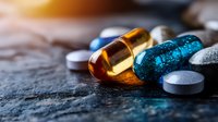 Colorful pharmaceutical capsules and tablets scattered on dark textured surface with warm lighting for medical healthcare and medicine concepts.
