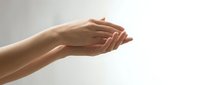 Soft female hands cupped together against a light background, showcasing smooth skin and natural nails for beauty and skincare concepts.