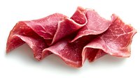 Fresh sliced prosciutto ham arranged in delicate folds showing marbled texture and rich pink color against white background, isolated for culinary design use.
