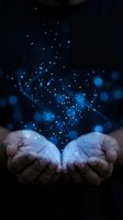 Cupped hands releasing glowing blue particles and light effects against dark background creating magical atmosphere for spiritual and technology concepts.
