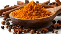 Aromatic turmeric powder in wooden spoon with cinnamon sticks, star anise and black peppercorns on white background, macro food photography for cooking.