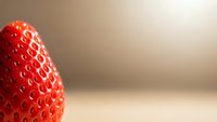Fresh ripe strawberry with detailed texture on soft beige background with copy space for food photography and healthy eating concepts.