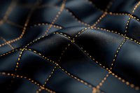 Luxury black leather texture with orange decorative stitching in diamond pattern, close-up macro shot showing detailed surface grain and craftsmanship.