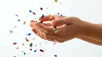 Hands catching colorful confetti pieces mid-air against white background, celebration moment for party, event, and festive occasions.