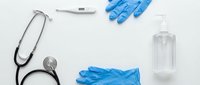 Medical equipment and protective gear including stethoscope, thermometer, blue nitrile gloves and hand sanitizer bottle arranged on clean white background.