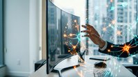 Business professional touching computer screen with digital network connections and glowing light effects in modern office environment.