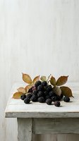 Fresh blackberries with autumn leaves arranged on rustic wooden surface against white backdrop. Ripe berries with foliage for food styling, culinary projects, and seasonal marketing materials.
