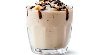 Creamy chocolate milkshake with whipped cream and chocolate chips in glass cup isolated on white background for dessert menu and cafe advertising.