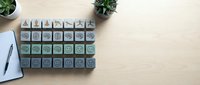Wooden rubber stamps with various icons and symbols arranged on desk with notebook, plants and pen for creative design projects and crafting.