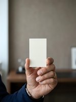 Person holding blank white card in hand, displaying empty space for custom text or branding in office environment.