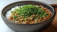 Hearty lentil curry served in rustic ceramic bowl with white rice and fresh chopped herbs, showcasing rich textures and vibrant colors in natural lighting.