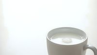 White ceramic mug filled with fresh milk on clean background for breakfast beverage and dairy product concepts.