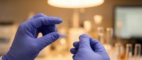 Medical researcher in purple latex gloves examining test tube sample in modern laboratory setting for scientific analysis and pharmaceutical research.