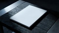 Blank white paper sheet on dark wooden table surface with dramatic lighting for mockup presentations and design templates.