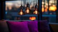 Cozy evening interior with vintage Edison bulb pendant lamps glowing warmly above purple cushions on sofa, sunset view through window creates atmospheric ambiance.