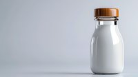Fresh milk in glass bottle with wooden cap on light background, minimalist composition with copy space for dairy product marketing and design.