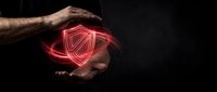 Male hand holding glowing red neon shield symbol against dark background, representing cybersecurity, data protection, and digital safety for technology concepts.