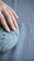 Woman hand with wedding ring touching smooth stone sphere for spa wellness meditation and mindfulness relaxation therapy concept.