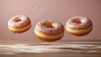 Levitating pink glazed donuts with rainbow sprinkles floating above wooden surface against pink background. Sweet pastry food photography for bakery marketing.