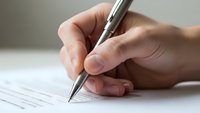 Close-up of hand holding pen writing on document paper. Business professional signing contract or form. Office work and paperwork concept.