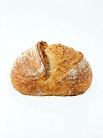 Artisan sourdough loaf with crispy crust and flour dusting, isolated on white background for bakery, food, and culinary design projects.