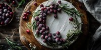 Festive cake decorated with sugared cranberries and rosemary wreath on wooden board, perfect for holiday entertaining.