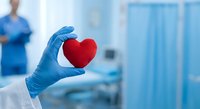 Healthcare professional holding red heart symbol in medical facility representing cardiology care and compassionate treatment services.