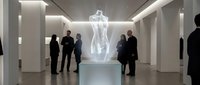 Visitors admiring translucent holographic female figure sculpture in modern white gallery space with LED lighting and minimalist architecture.
