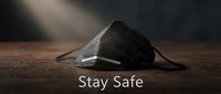 Black protective respirator mask on wooden surface with dramatic lighting and Stay Safe motivational text for health campaigns.