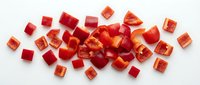 Fresh red bell pepper diced into small uniform cubes scattered on white background, perfect for cooking recipes and culinary presentations.