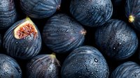 Fresh ripe black figs with water drops and one cut fig showing pink flesh interior, arranged in dark moody composition for food photography and design.