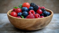 Fresh mixed berries including strawberries, blueberries, blackberries and raspberries in wooden bowl on rustic background, healthy organic summer fruit.