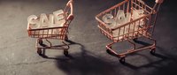 Two miniature rose gold shopping carts carrying SALE letters on dark stone surface, retail discount promotion concept for banners and ads.