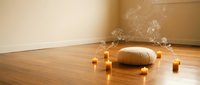 Meditation cushion with burning candles and incense smoke in peaceful zen room with wooden floor for mindfulness practice and spiritual wellness.