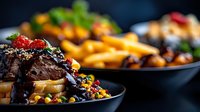 Juicy beef steak topped with berries and herbs served with golden french fries on black plate. Dark moody restaurant atmosphere with selective focus.