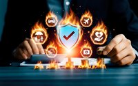 Businessman hands protecting digital shield with security icons surrounded by flames representing cybersecurity protection and data safety measures.