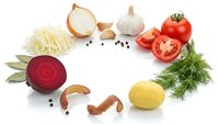 Fresh organic vegetables and herbs arranged on white background including sliced beetroot, tomato, onion, garlic, cabbage and dill for healthy cooking.