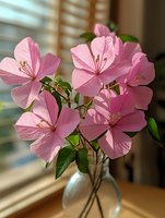 Cluster of pink geranium flowers with delicate petals in clear glass vase, green foliage visible, natural sunlight streaming through window, indoor home decor arrangement.