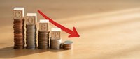 Declining financial graph with stacked coins showing economic downturn and market recession on wooden background for business analysis presentations.