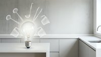 Light bulb with creative idea symbols radiating outward in modern minimalist kitchen interior with clean white cabinets and concrete wall background.