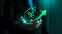 Businessman holding glowing house with percentage symbol and upward arrow representing mortgage rates, real estate investment growth and property market trends.