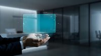Businessman hand holding glowing blue digital screen with particle effects in modern office environment, representing technology, data, and innovation.