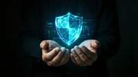 Hands holding glowing digital shield with network connections on dark background, representing cybersecurity, data protection, and secure technology solutions.