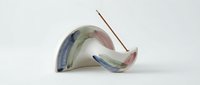 Curved ceramic vessel with flowing watercolor glaze in blue, green, and rose tones, isolated on white background for design and artistic projects.