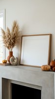 Autumn mantel decor with blank wooden frame mockup, pampas grass, pumpkins, and terracotta vase on concrete fireplace shelf.