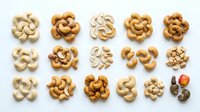 Assorted cashew nuts arranged in groups on white background, showcasing different roasting levels and varieties for culinary, nutritional, and food photography purposes.